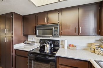 A kitchen with brown cabinets and a black stove top oven.